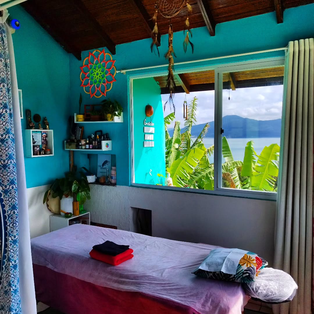 Sala de atendimento Cura em Movimento com maca, mandala e vista para a natureza